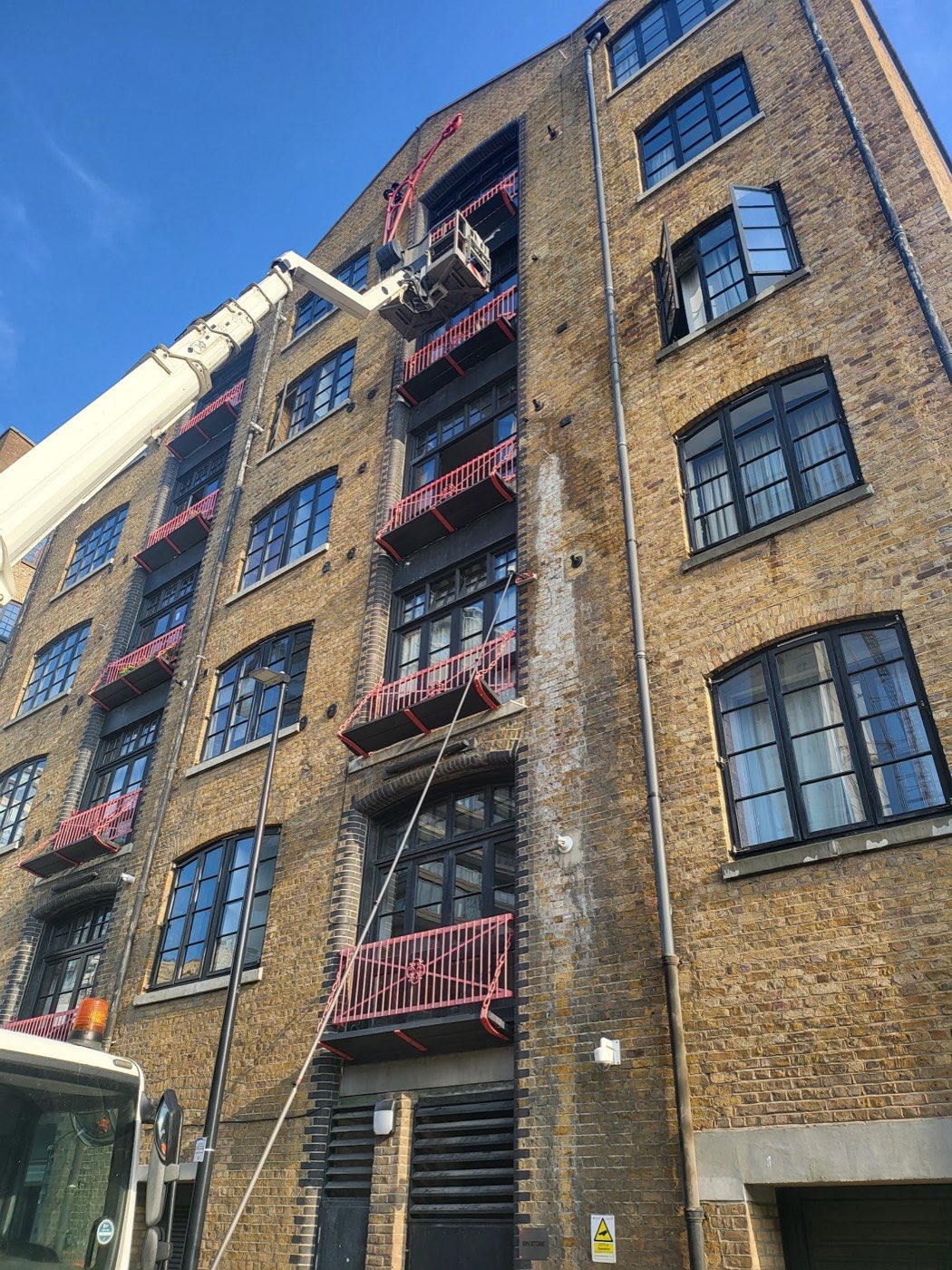 A1 Shines cleaning high warehouse windows in East London from a cherry picker